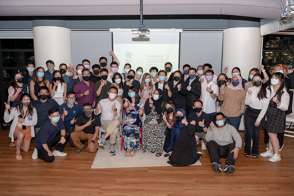 Group of masked people pose in front of projection screen at NYC Kopi Session event.
